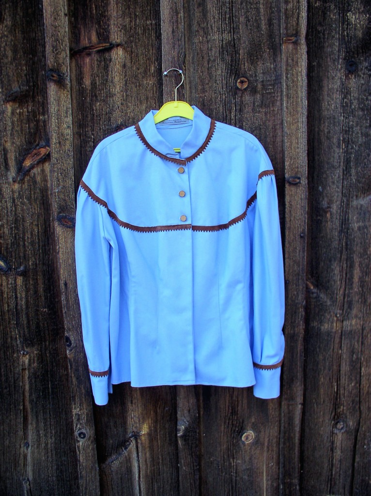 Blå bomullsblus med brunt mocka band vid hals, ok och manschett knäppning fram delvis dold knäppning